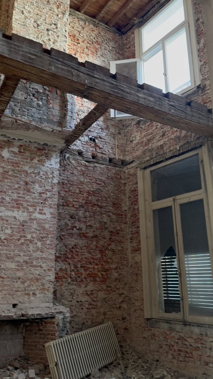 An old room opened to brick, a timber beam, and a sash window.