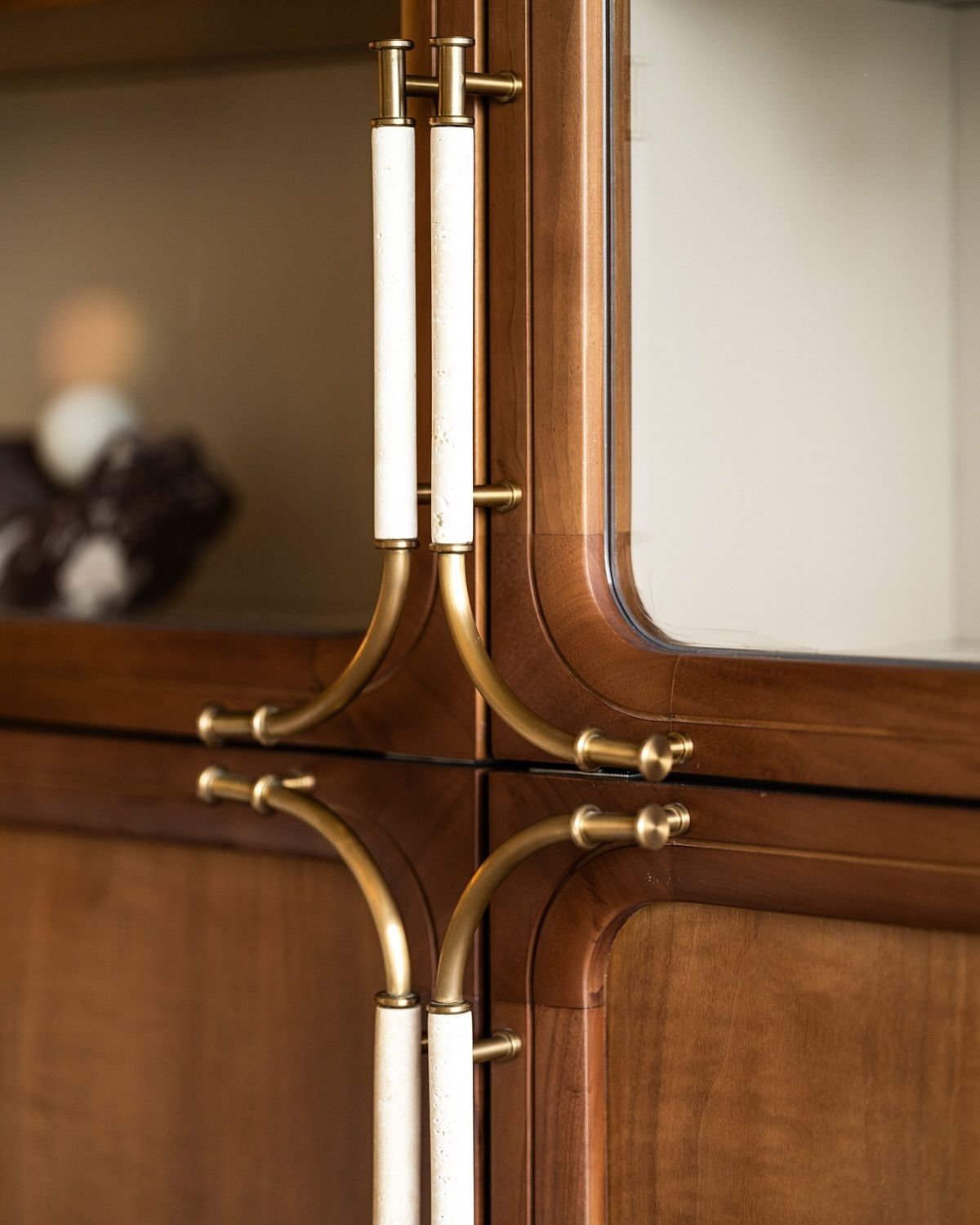 Close view of curved brass pulls with pale grips on dark wood cabinet doors.